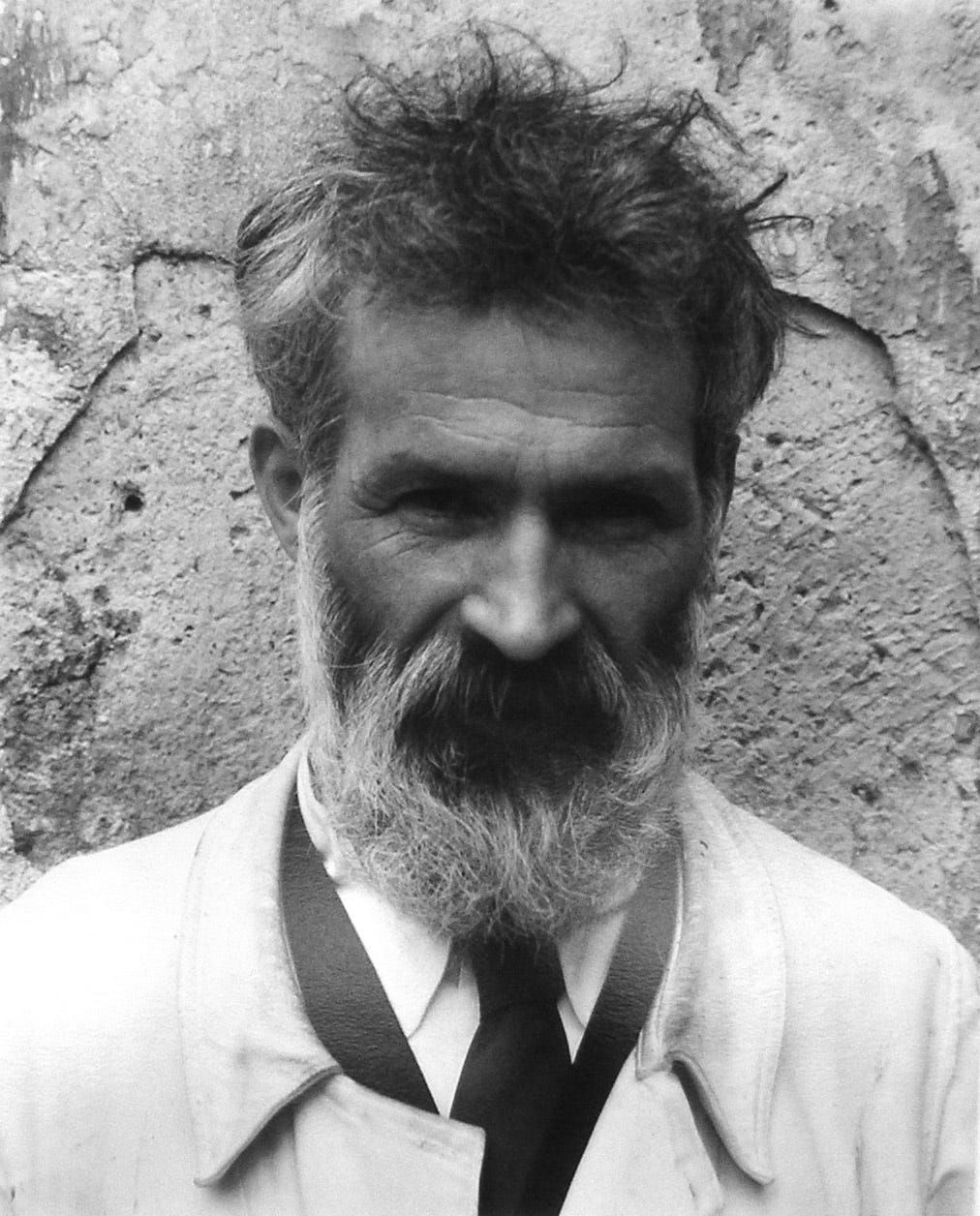 Black and white portrait of the sculptor Constantin Brancusi, bearded, his face and shoulders seen in front of a stone wall. Black and white portrait of the sculptor Constantin Brancusi, bearded, his face and shoulders seen in front of a stone wall.