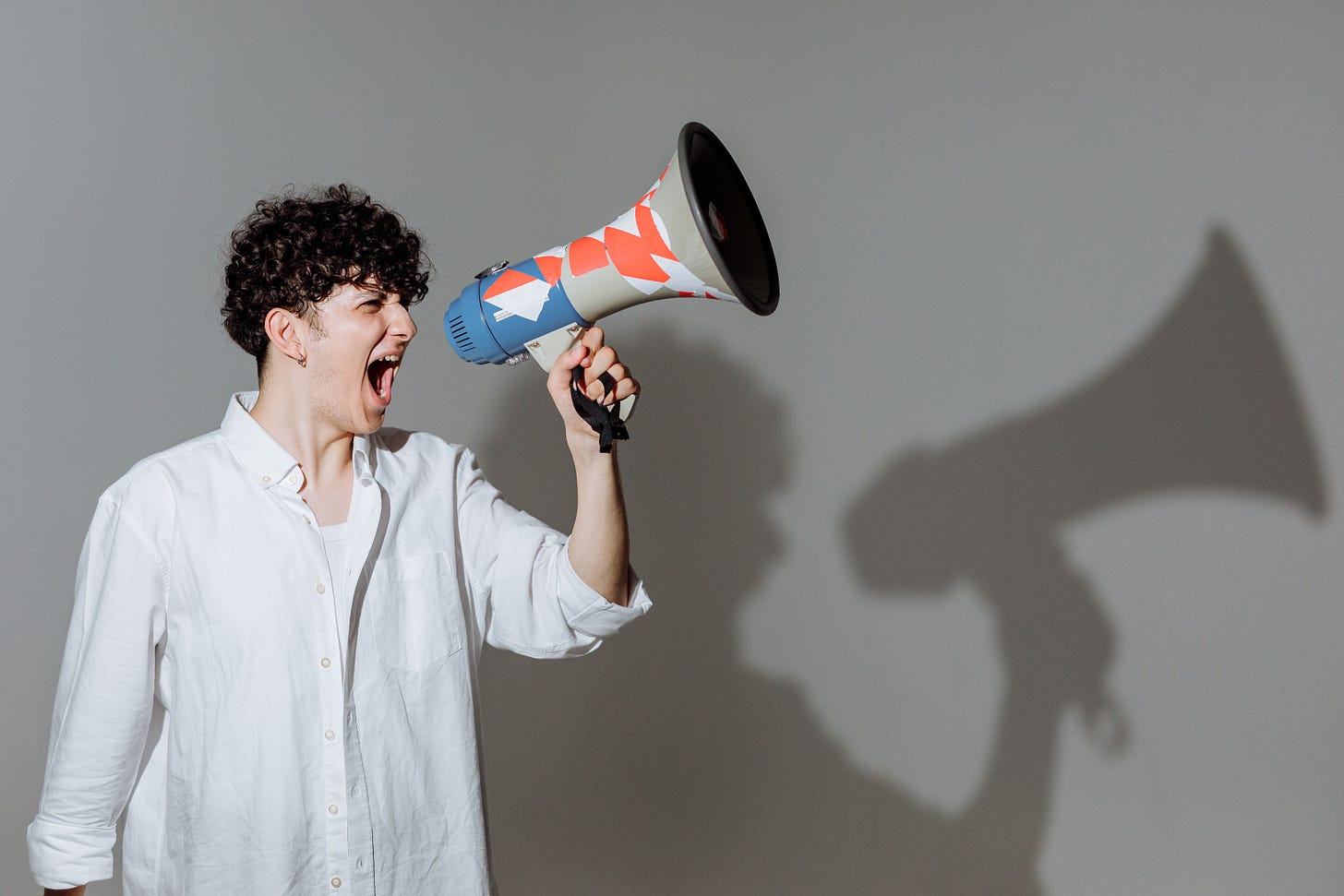 man shouting into horn to have his needs heard