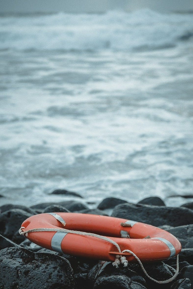 red inflatable ring on black rock near body of water during daytime red inflatable ring on black rock near body of water during daytime