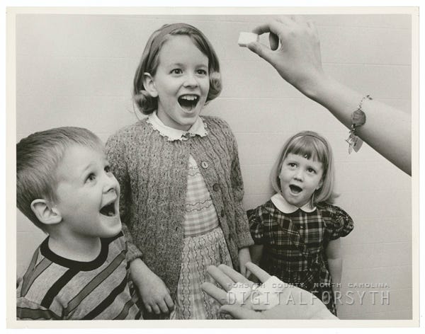 Children taking the polio vaccine on sugar cubes, 1964.