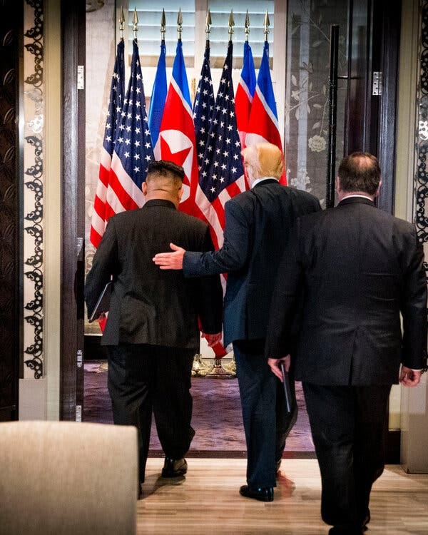 Donald Trump and Kim Jong-un, seen from behind, walk into a room with U.S. and North Korean flags visible beyond. Donald Trump and Kim Jong-un, seen from behind, walk into a room with U.S. and North Korean flags visible beyond.