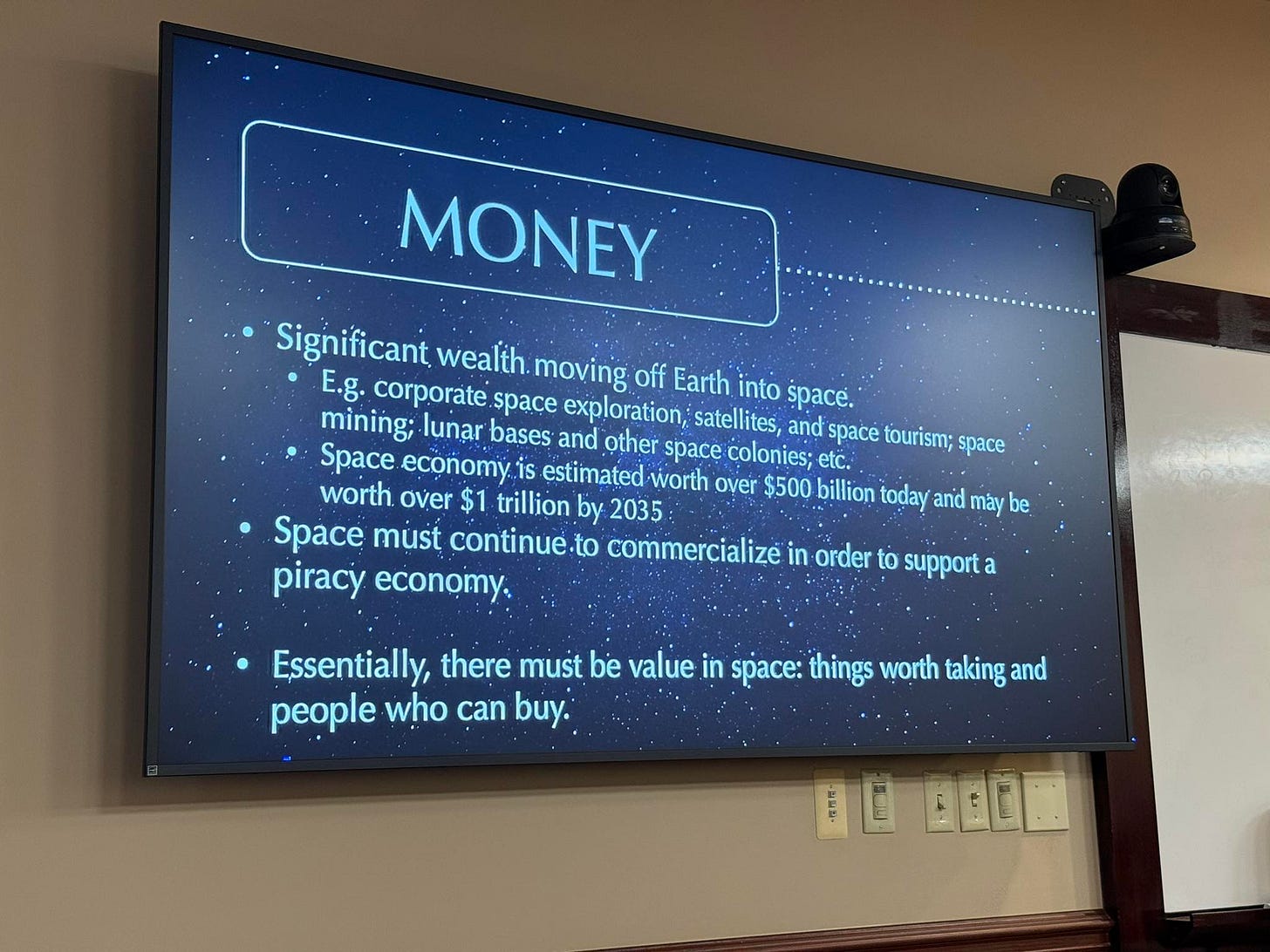 May be an image of television and text that says 'MONEY Significant wealth. moving off Earth into space. E.g. corporate space exploration, satellites, and space tourism; space mining; lunar bases and other space colonies; etc. Space economy.. estimated worth Over $500 billion today and mày be worth over $1 trillion by 2035 Space must continue.to commercialize in order to support a :e piracy economy, Essentially, there must be value in space: things worth taking and people who can buy.'