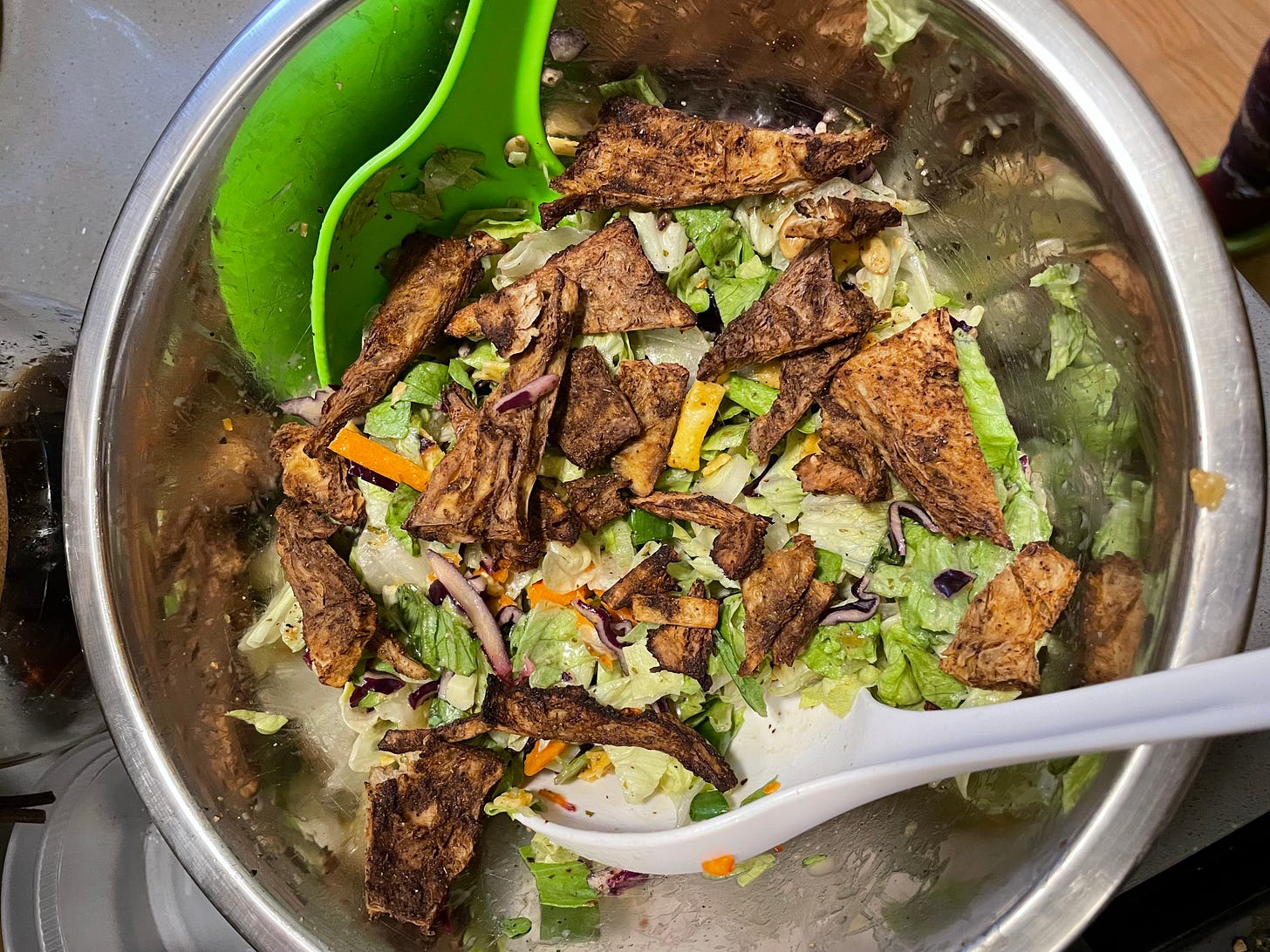 mixing bowl of southwestern salad with crispy tofu triangles with salad tongs in bowl