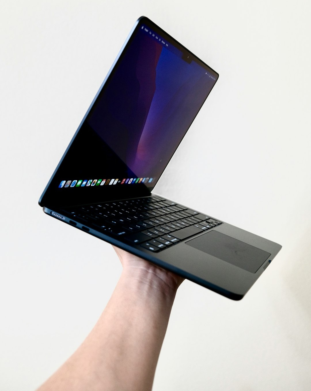a hand holding a laptop
