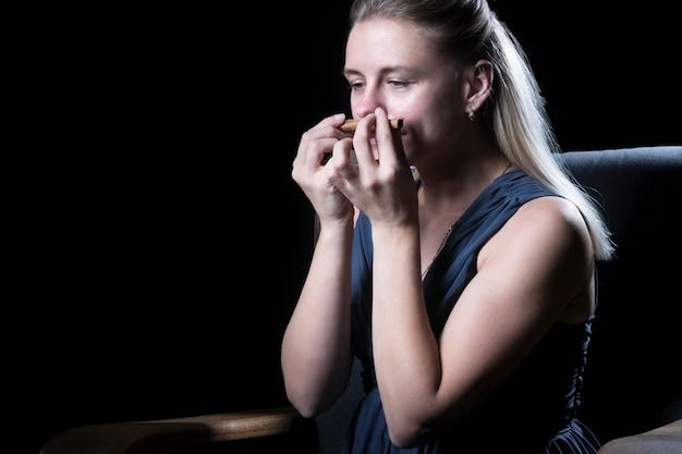 Hermosa mujer sentada en una silla olfateando un cigarro, aislada en un fondo negro