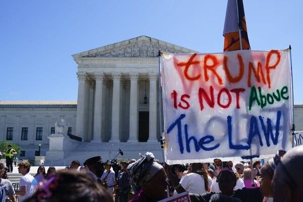 Protesters outside the Supreme Court building, with a large banner that reads: “Trump is not above the law.” Protesters outside the Supreme Court building, with a large banner that reads: “Trump is not above the law.”