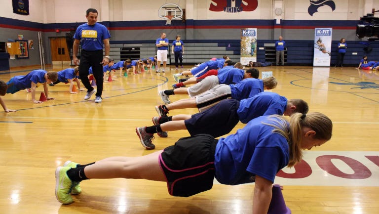 Highschool gym glass doing pushups while coaches watch