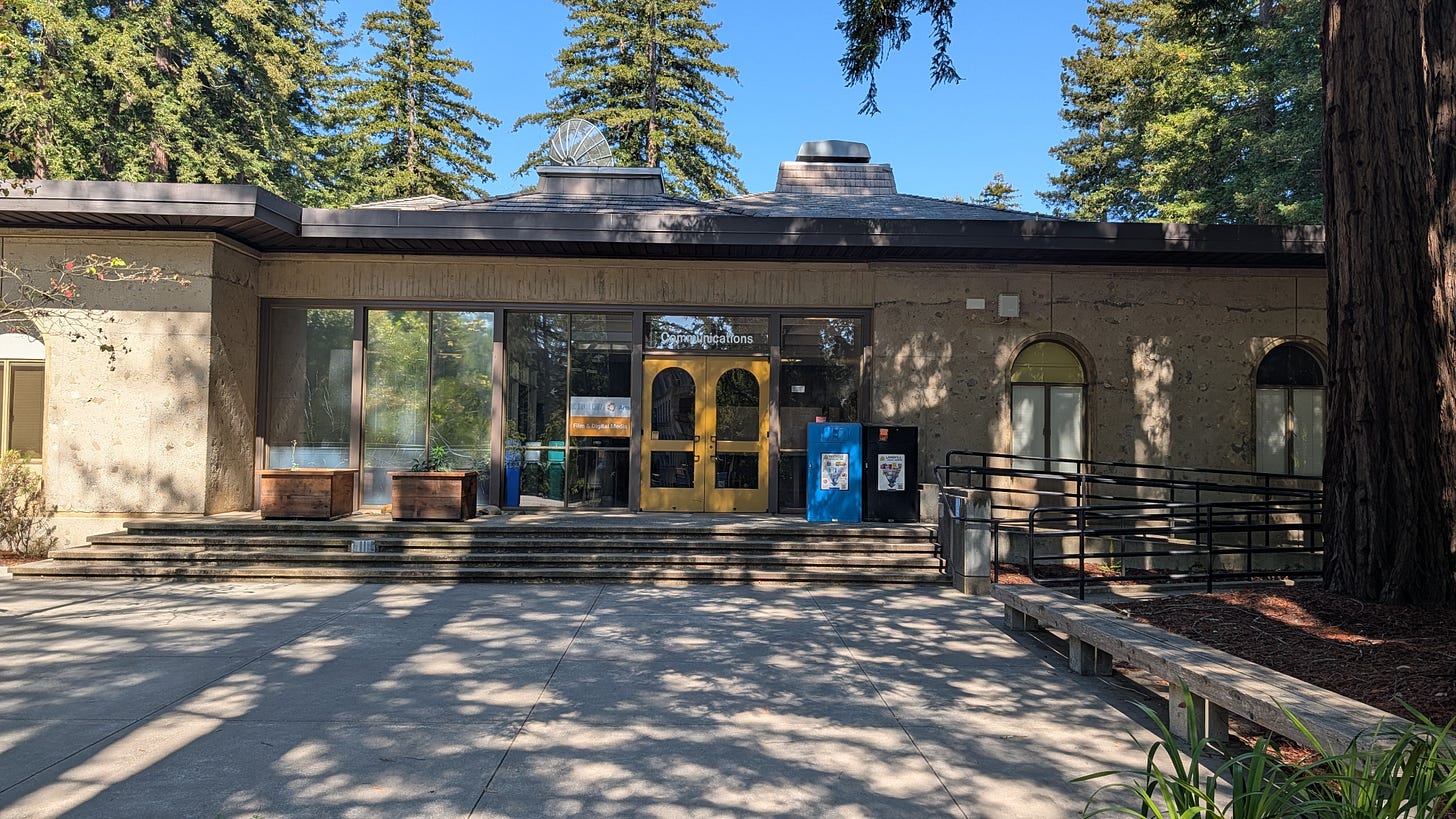 The front entrance of the Communications building, with Film and Digital Media signage and a satellite dish visible on the roof.