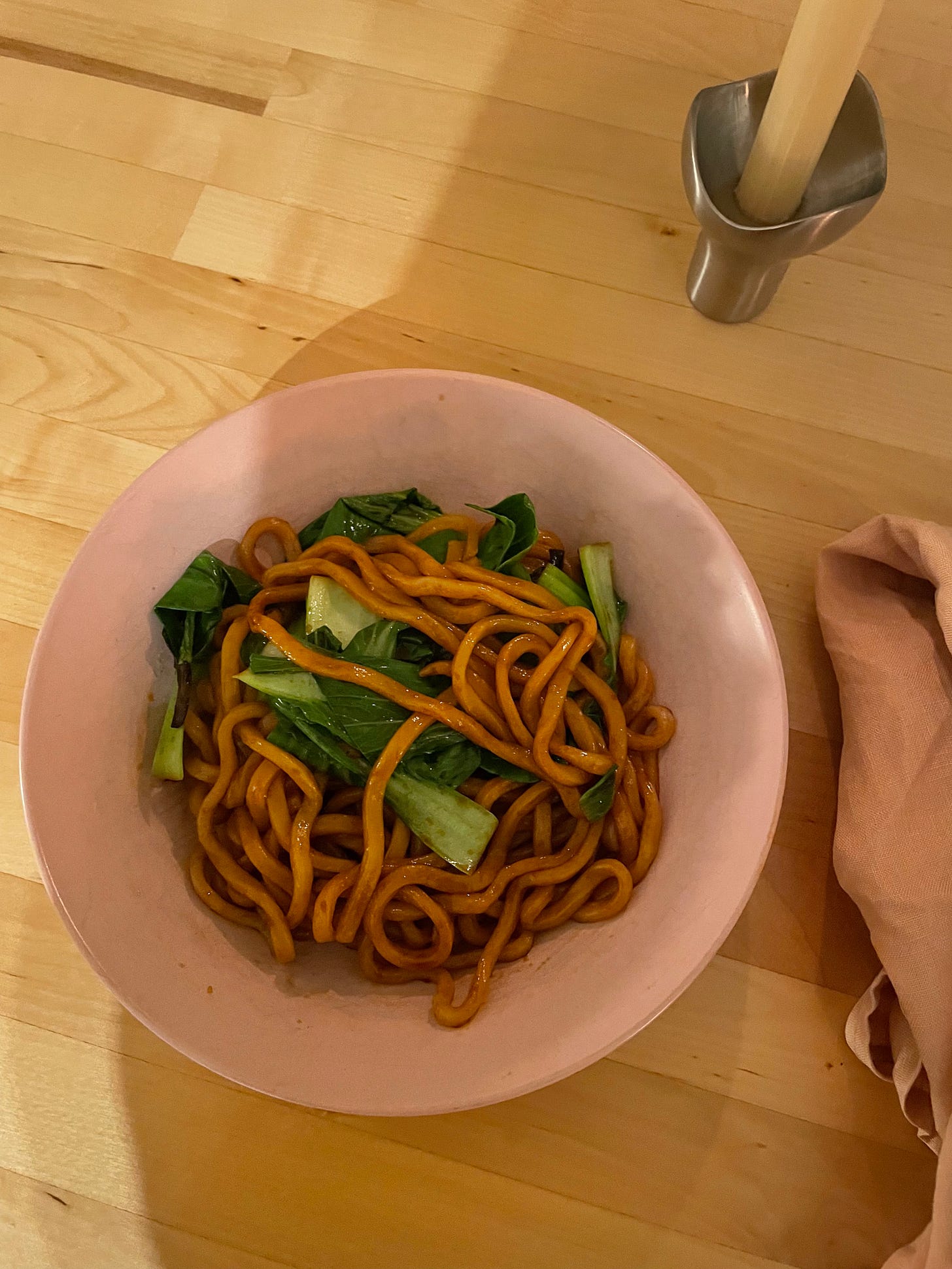 A bowl of udon noodles with scallion oil and bok choy