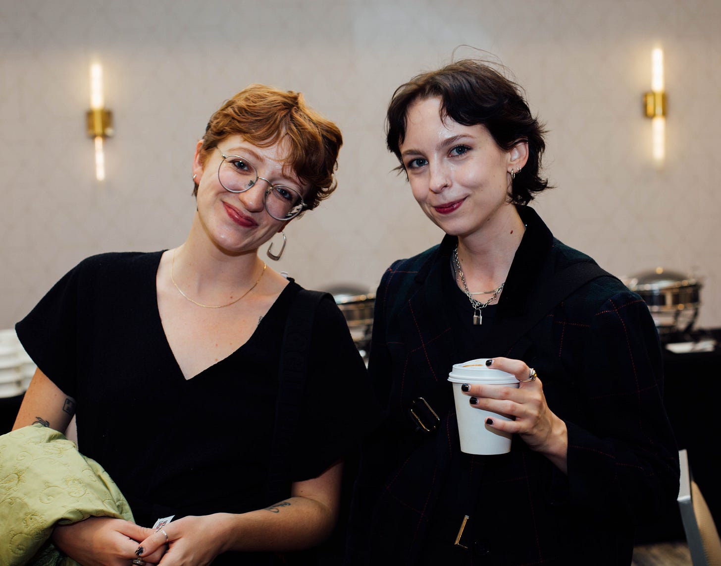 the substackers, both in black, captured from the waist up before a beige marriott ballroom background.