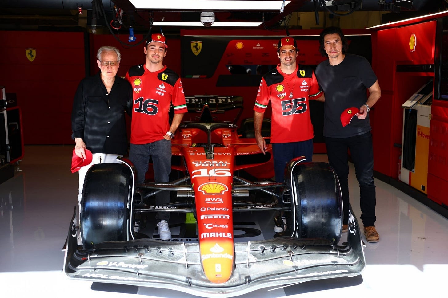 Michael Mann and Adam Driver posing with Ferrari drivers Charles Leclerc and Carlos Sainz with the Ferrari F1 car