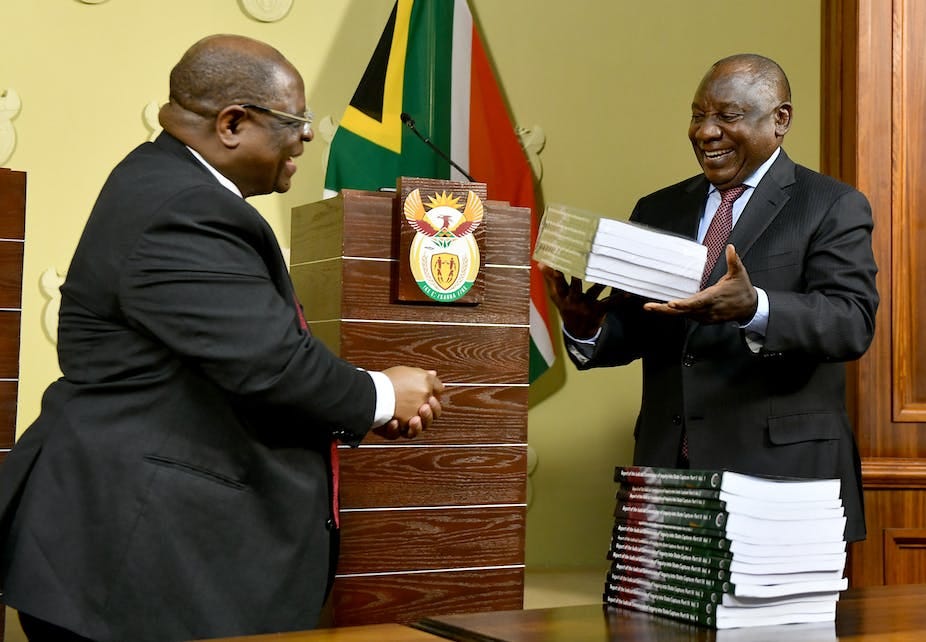 A man receives volumes of reports from another. A man receives volumes of reports from another.