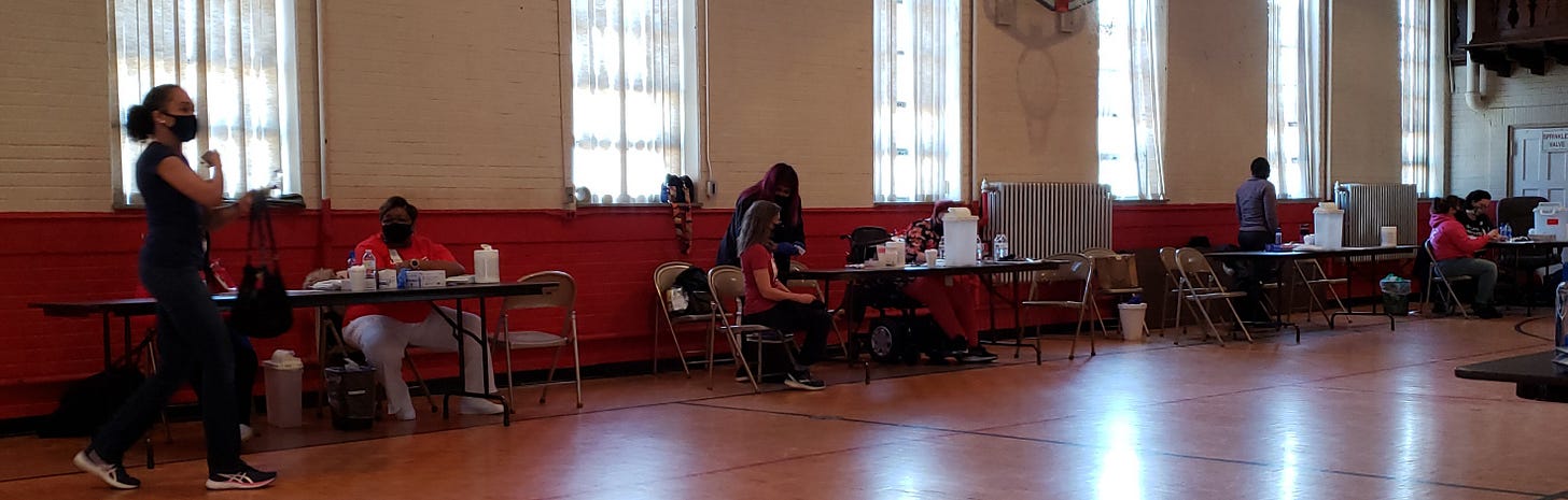 Color photo of a vaccination event in an old gymnasium in St. Louis.