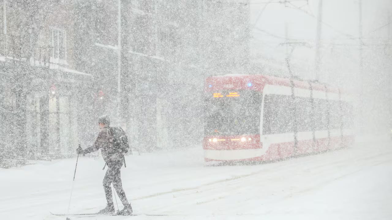 A person cross-country skiing across a streetcar track during a shock snowstorm in Toronto, 2026