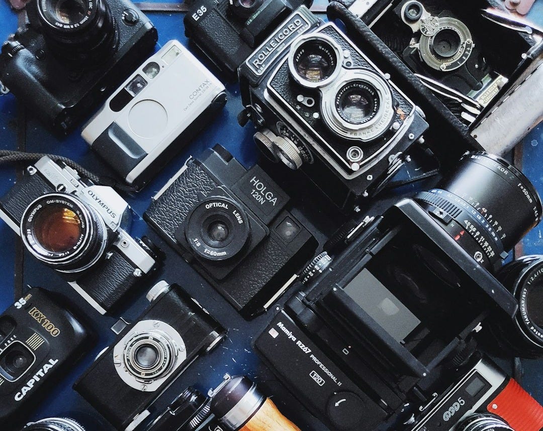 a table topped with lots of different types of cameras