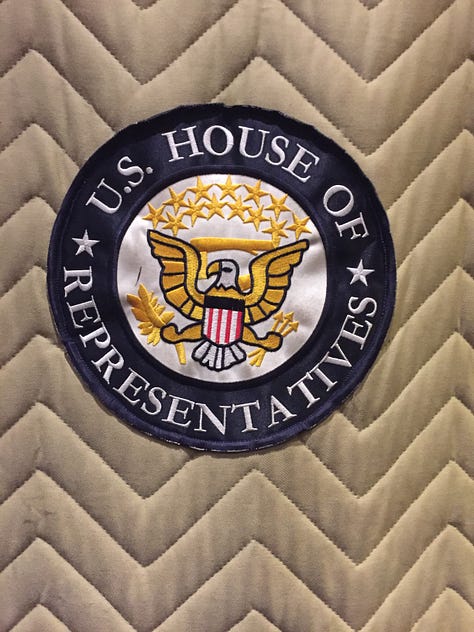 Nine images from a trip to the U.S. Capitol. Picture #1: a woman and a man walking through the halls of Congress. Picture #2 The Capitol rotunda. Picture #3: A woman and a man admiring art on a wall. Picture #4: Memoir coach Christine Wolf in the National Archives. Picture #5 a sign in an elevator of the House of Representatives, Picture #6: a man walking through a hallway. Picture #7 a view of the capitol from a window. Picture #8 Two elevator doors. Picture #9: a hallway with ornate ceilings.