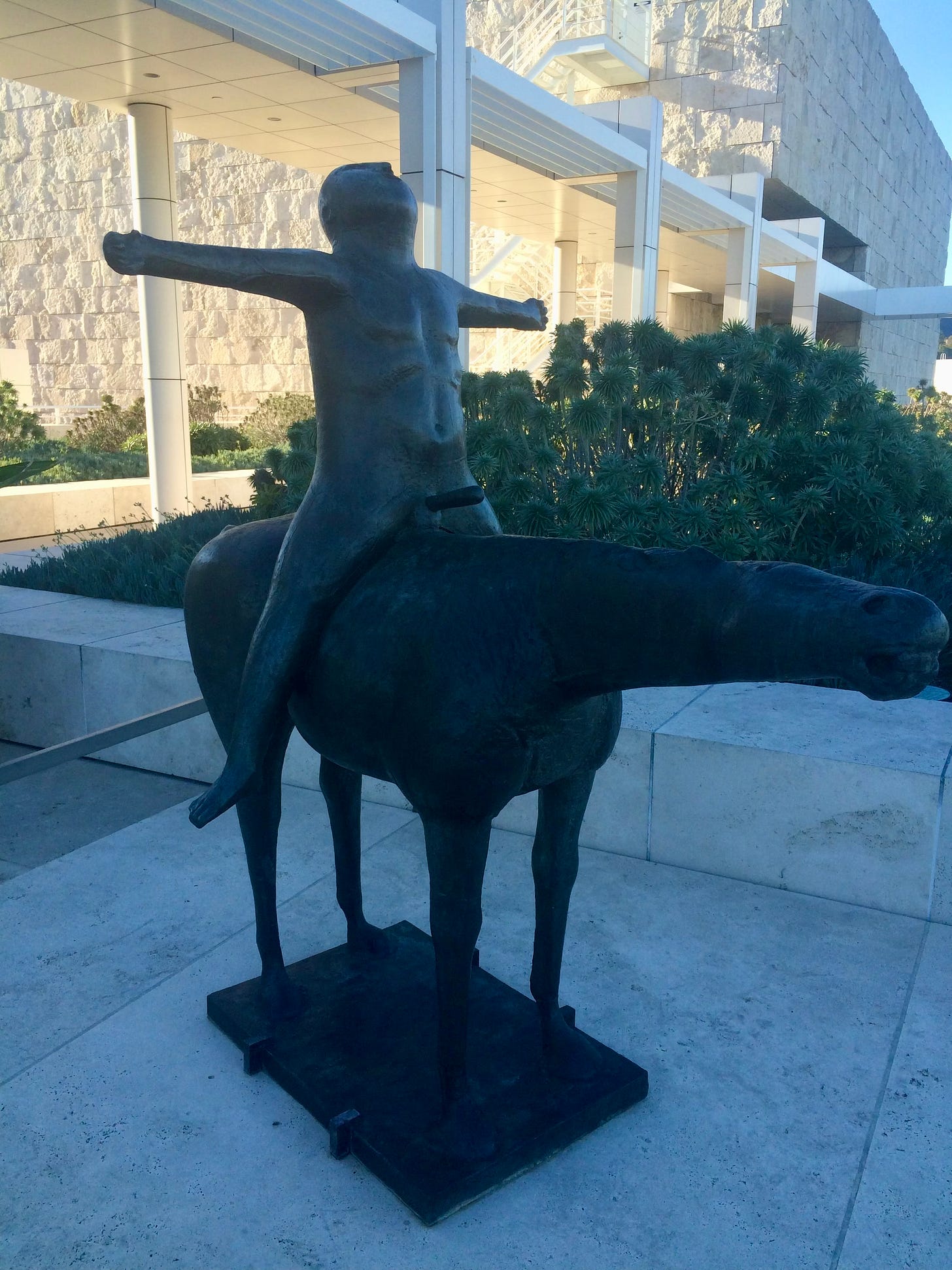 A photo of a sculpture by Marino Marini of a naked ride on a horse with their arms spread wide
