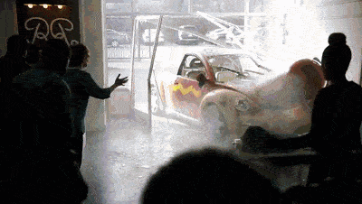 A small car smashes through the glass front of a showroom, sending shards and smoke as startled onlookers recoil. A small car smashes through the glass front of a showroom, sending shards and smoke as startled onlookers recoil.