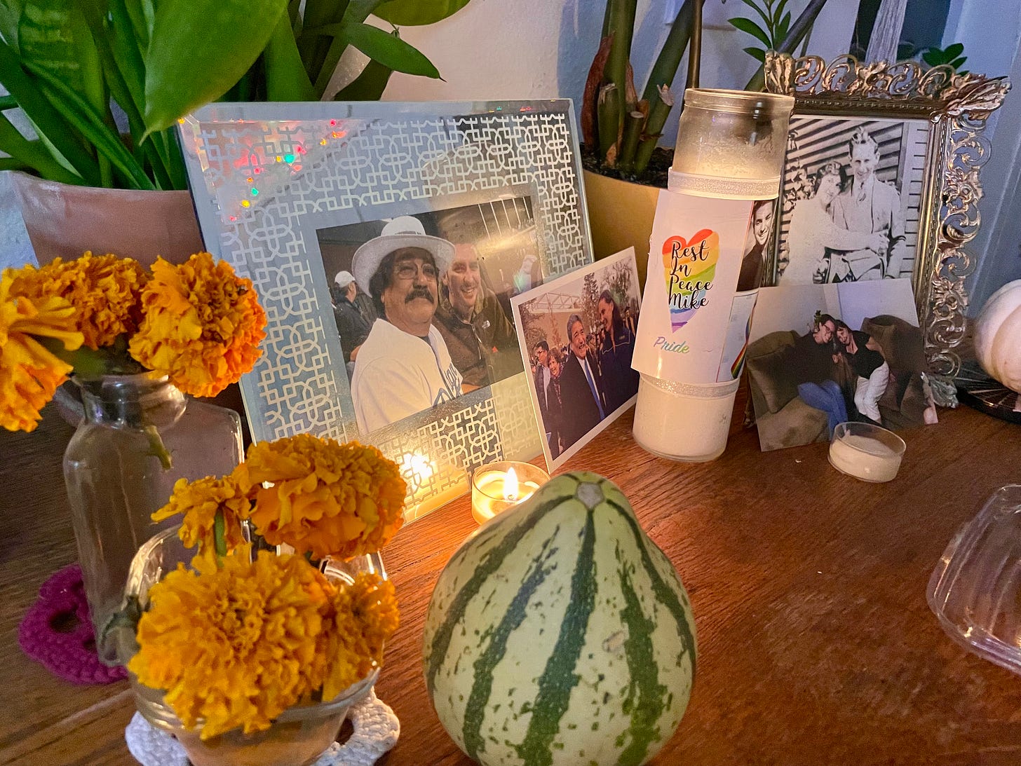 Orange flowers (marigolds) nestled amongst framed photos of loved ones, and lit candles