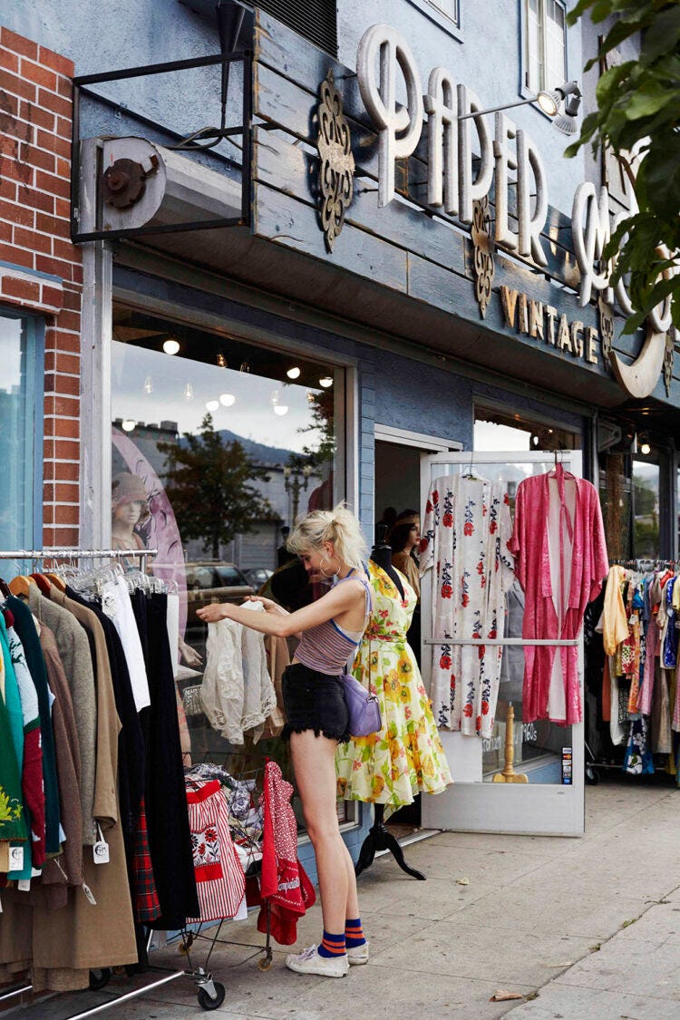 A woman looking at second-hand clothing outside a store