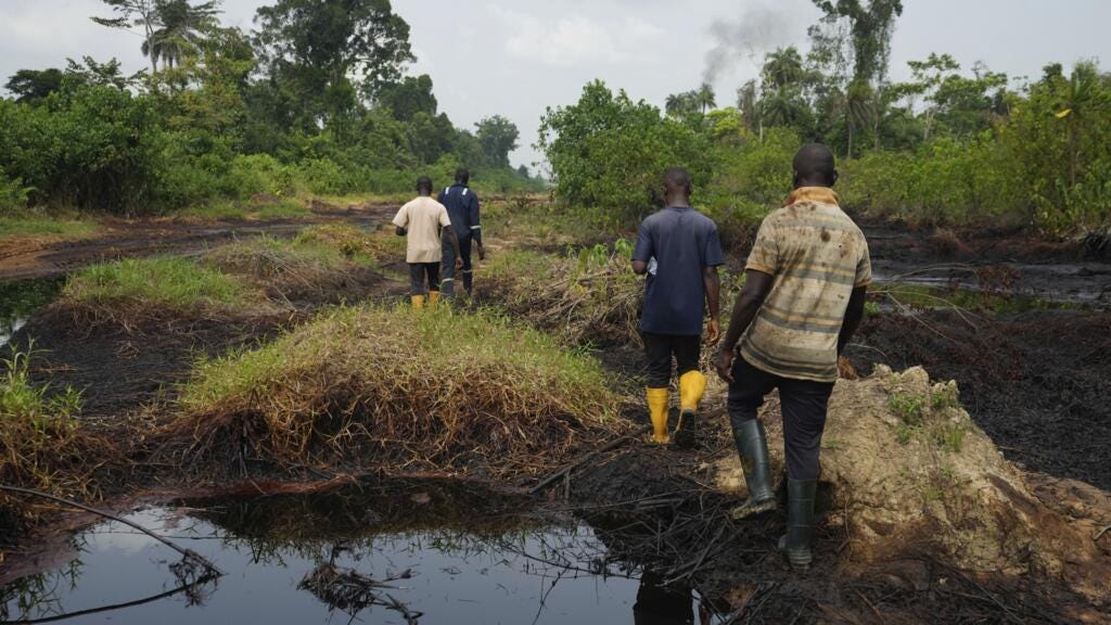 People walk amid an oil spill in the Niger Delta in village of Ogboinbiri, Nigeria, 11 December 2024.