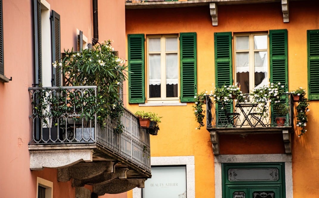 a building with green shutters and a balcony