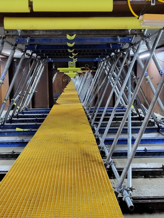 scaffolding above a yellow metal floor inside the viaduct, the light of the sky visible as a tiny dot on the horizon
scaffolding above a yellow metal floor inside the viaduct, the light of the sky visible as a tiny dot on the horizon
