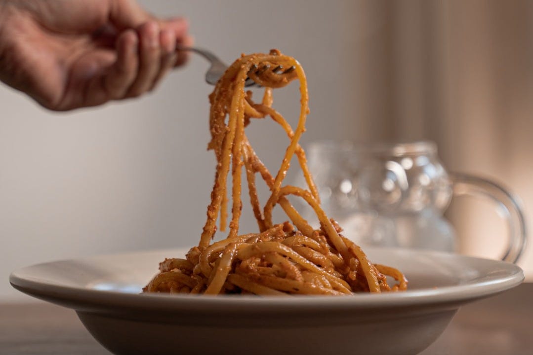 A plate of spaghetti being eaten with a fork A plate of spaghetti being eaten with a fork