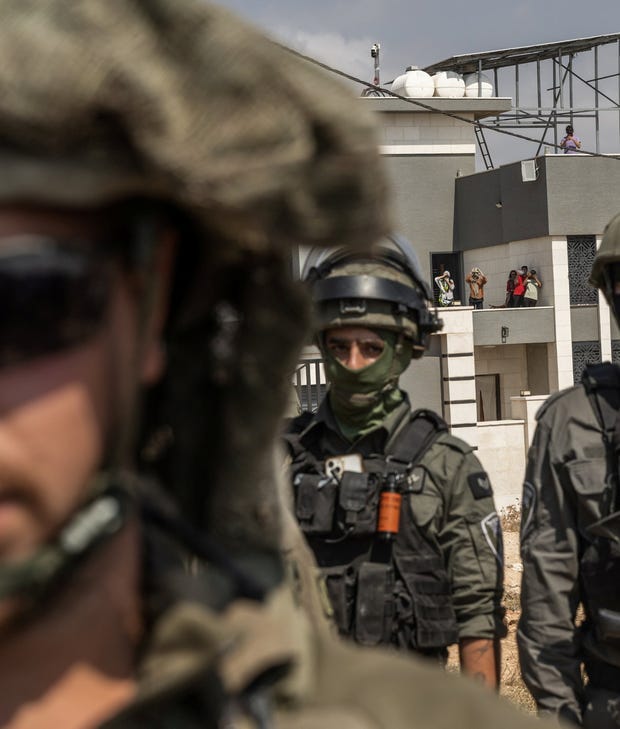 Israeli soldiers standing in front of a home where three Palestinian families are besieged in Qusra, northern West Bank, on Friday.