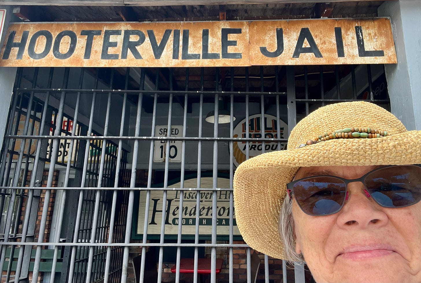 woman in hat in front of jail cell and sign Hooterville Jail woman in hat in front of jail cell and sign Hooterville Jail