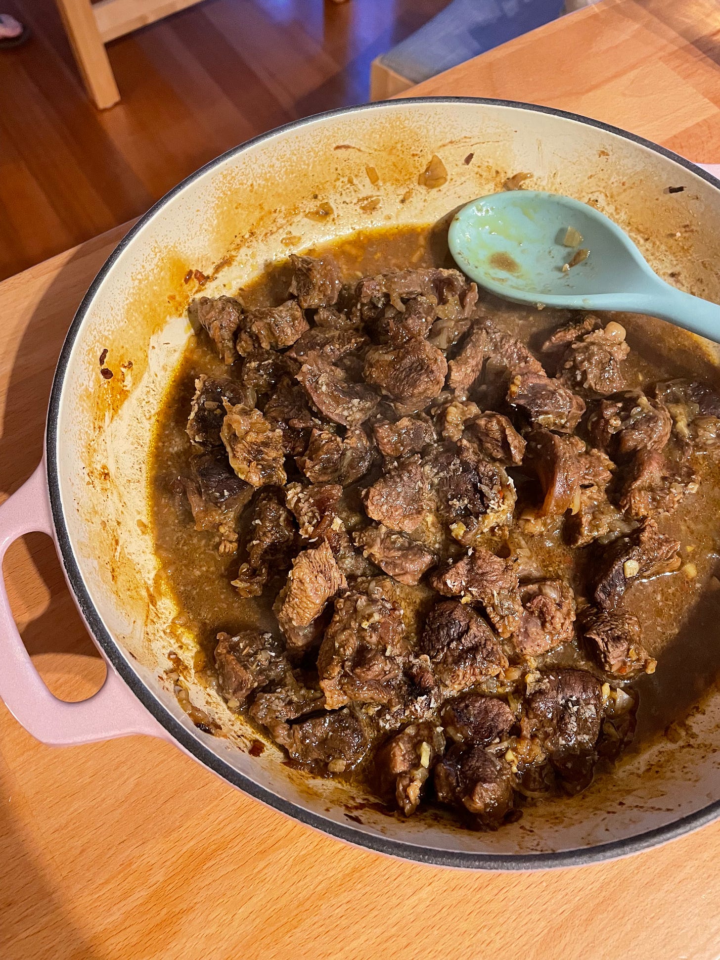 A pink dutch oven with oven baked beef rendang in sauce