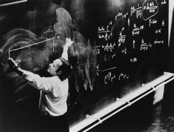 This may contain: a man writing on a blackboard with chalk