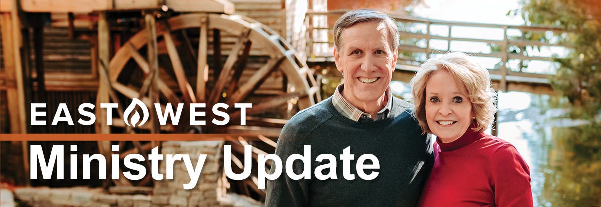 Image of a man and woman smiling in front of a water wheel.