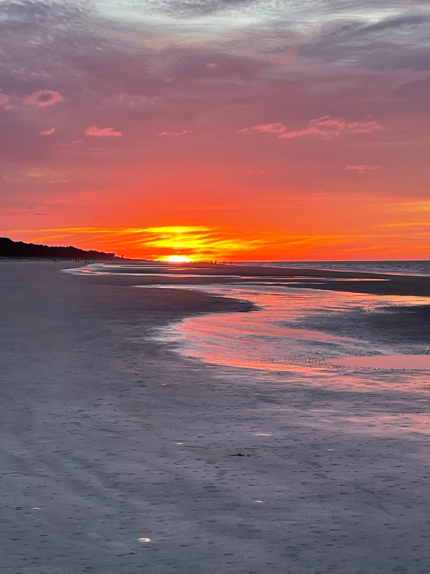 A vivid orange and pink sunset reflected across the beach and shoreline. A vivid orange and pink sunset reflected across the beach and shoreline.