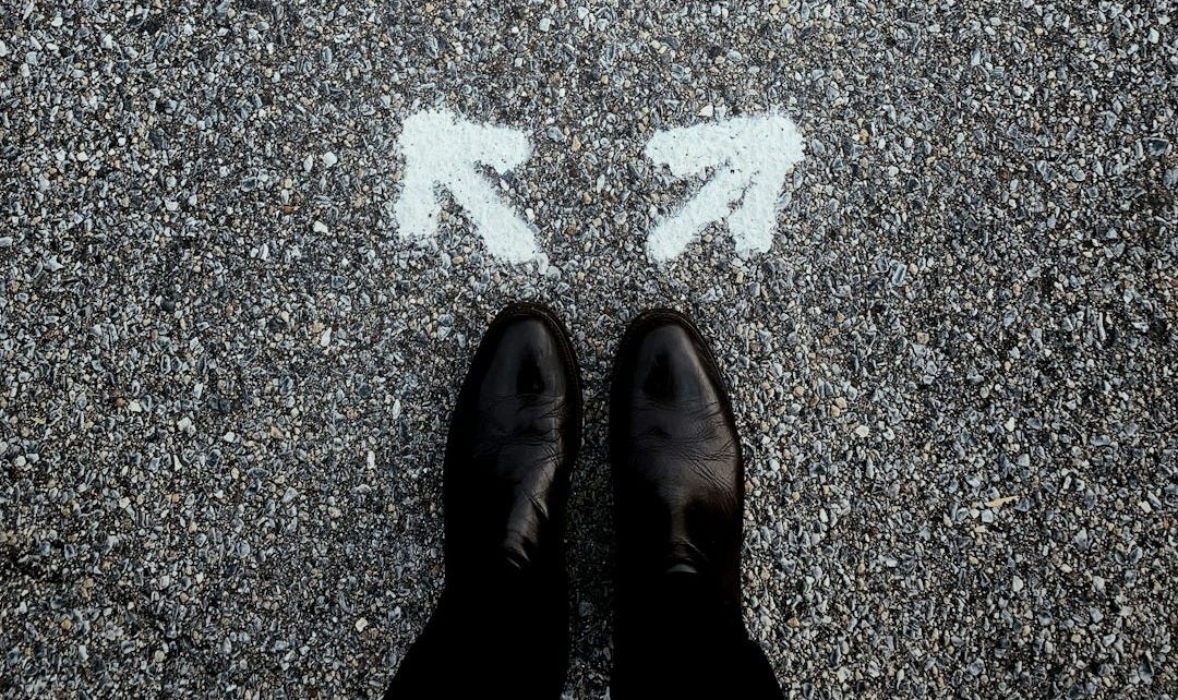 feet on asphalt between two directional arrows feet on asphalt between two directional arrows