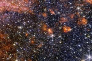 Stars, gas and cosmic dust in the Sagittarius B2 molecular cloud glow in near-infrared light, captured by Webb’s NIRCam instrument. The darkest areas of the image are not empty space but are areas where stars are still forming inside dense clouds that block their light.