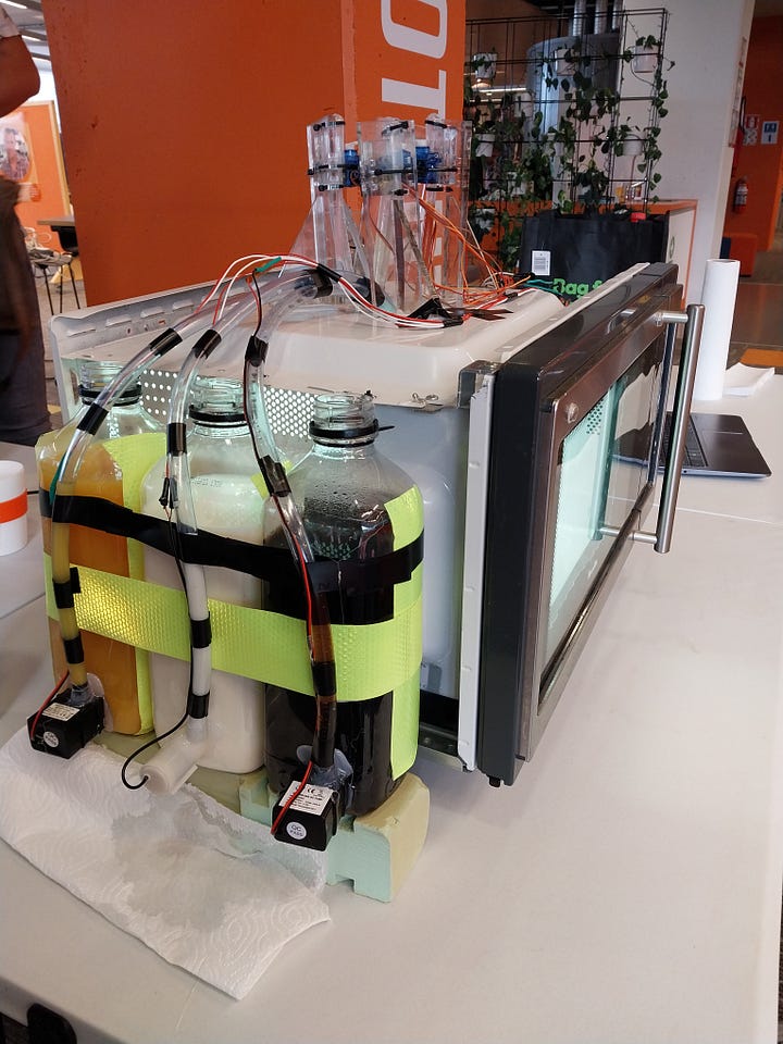 Images of a microwave modified to dispense drinks, one of which contains the author smiling beside the machine