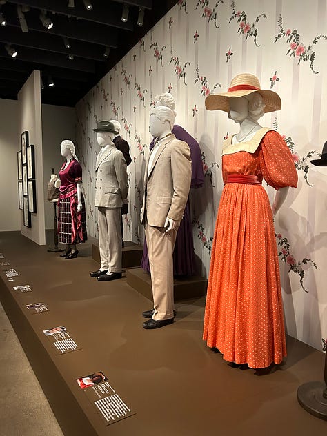 Viola Davis on a screen, costumes on mannequins, Marlee Matlin accepting her Oscar, an Oscar in a case, and photos of the Black Panthers from a documentary.