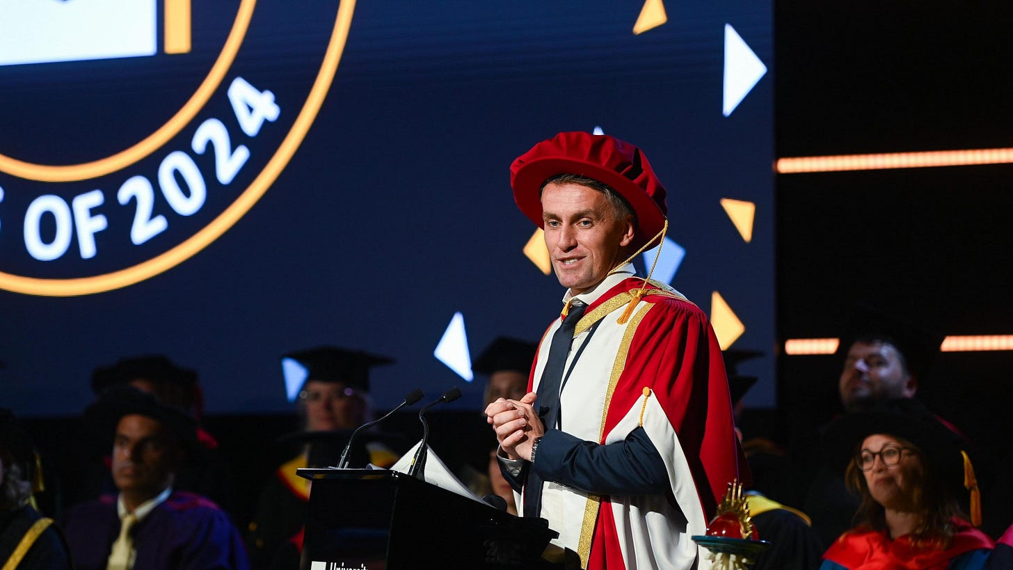 Kieran McKenna accepts an honorary doctorate from the University of Suffolk in full academic garb (including floppy red mortar board hat)