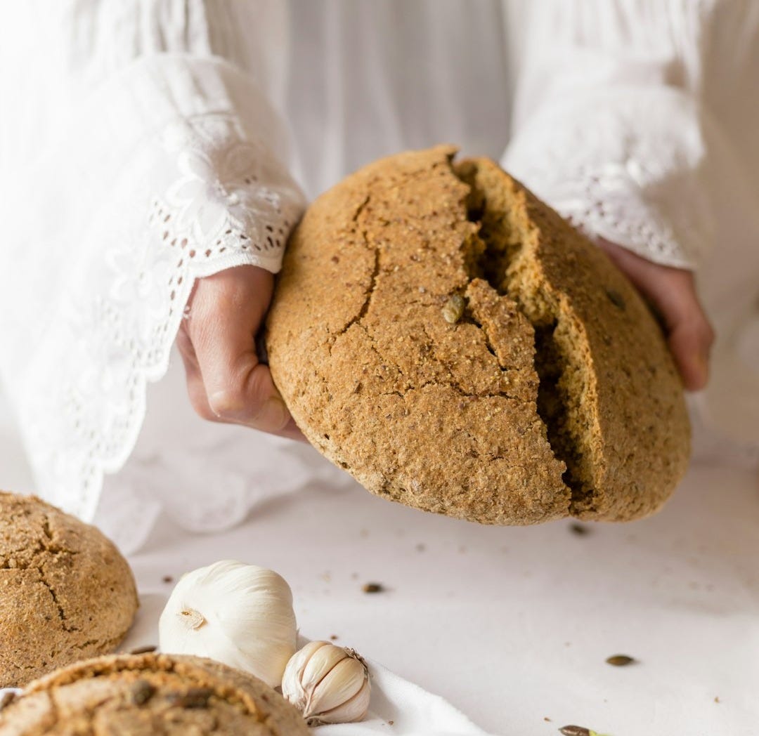 person in white long sleeve shirt holding brown round bread