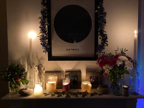 A view of a river. A couple smiling at the camera. A mantlepiece with candles and pictures.