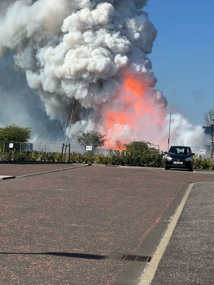 Large fire and smoke plume rising from a building.