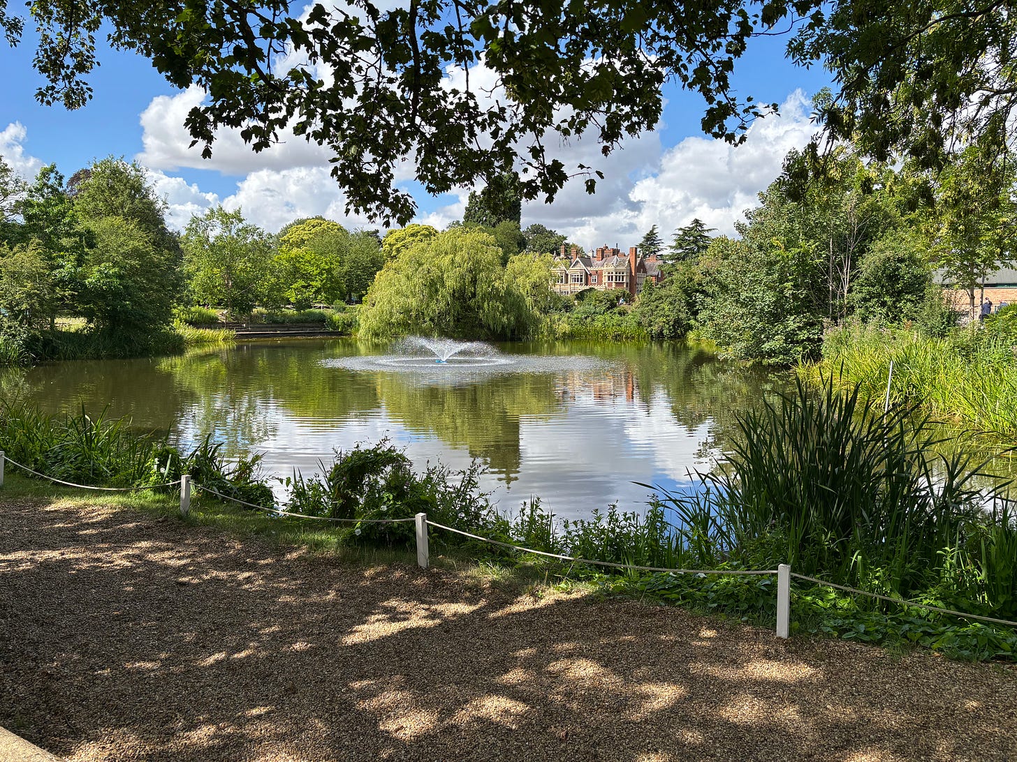 A small lake and fountain, surrounded by trees. 