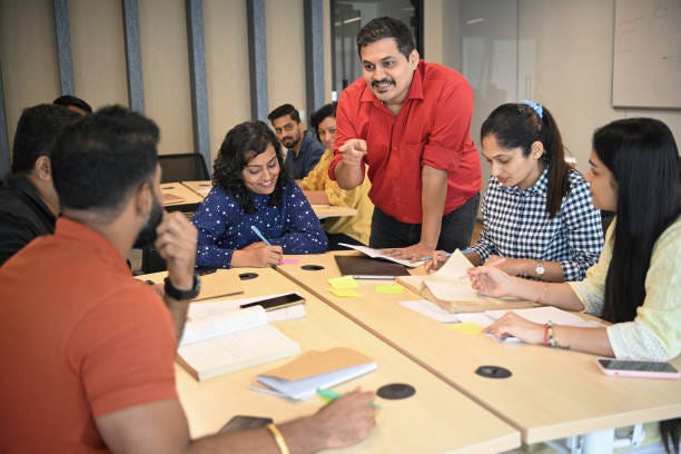 Confident Mid Adult male professor explaining mature adult students in the classroom stock photo