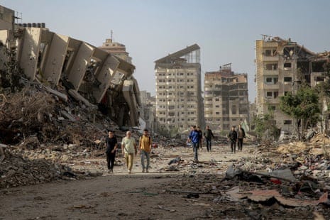 Palestinians walk amid rubble of destroyed buildings