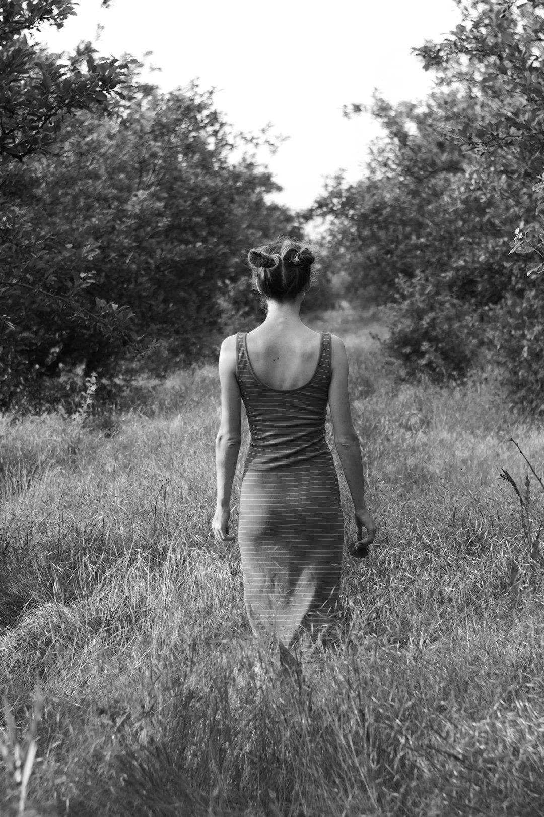 woman in orange tank dress standing on green grass field during daytime