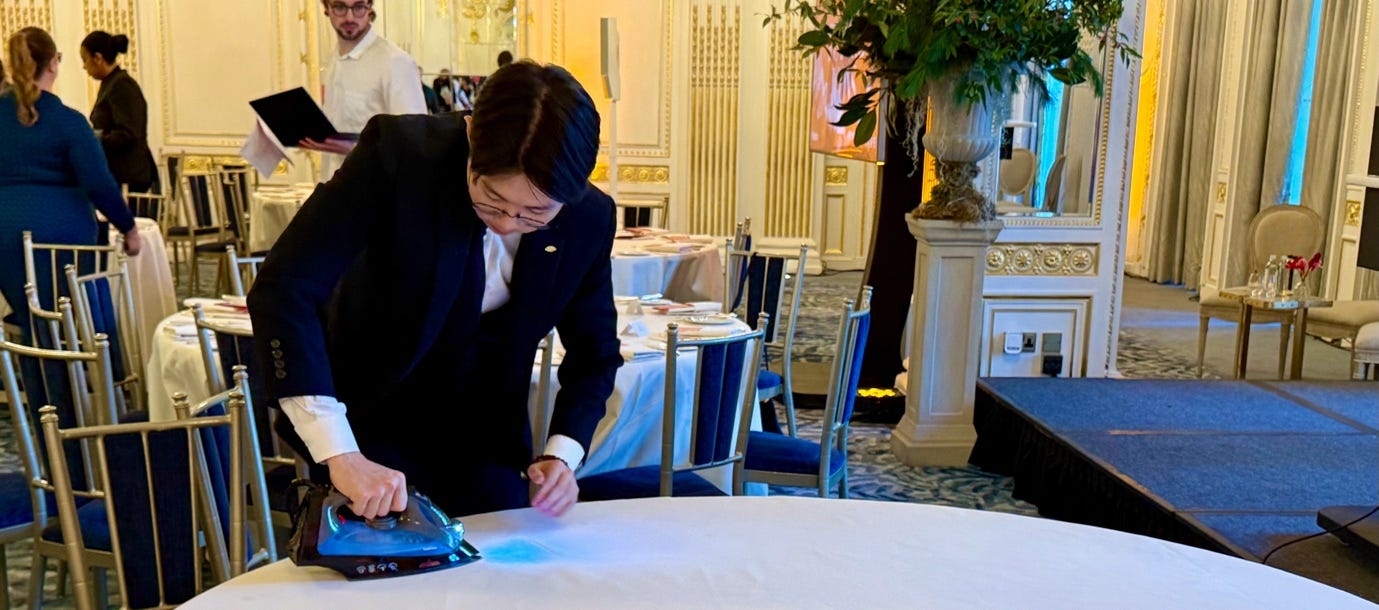 A person in a suit ironing a table

AI-generated content may be incorrect.