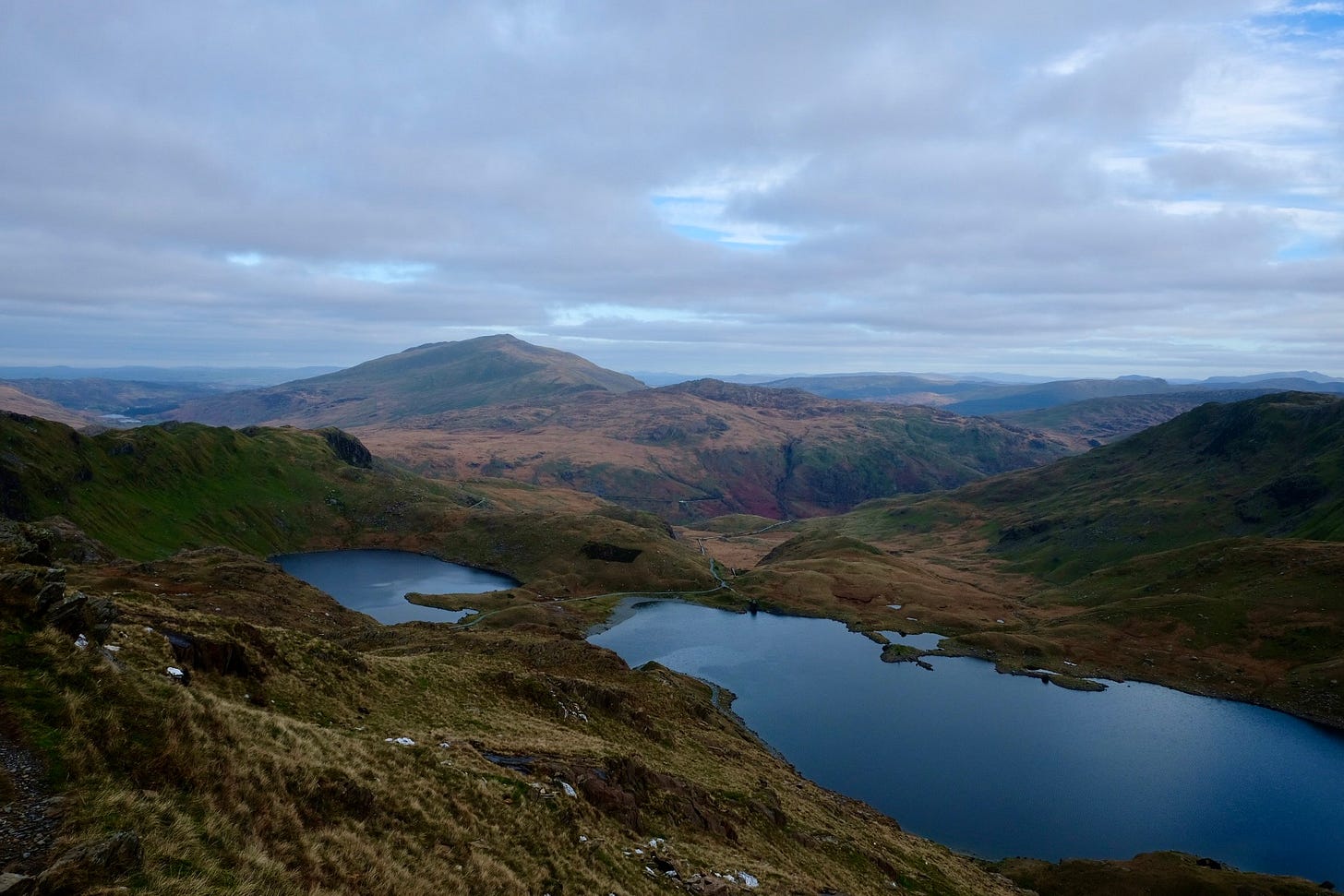 Peaks in Eryri National Park are visible under a cloudy sky, with small lakes in the foreground.