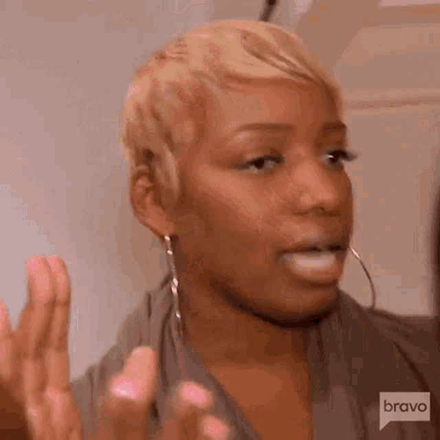 a woman with short blonde hair and hoop earrings is making a face .