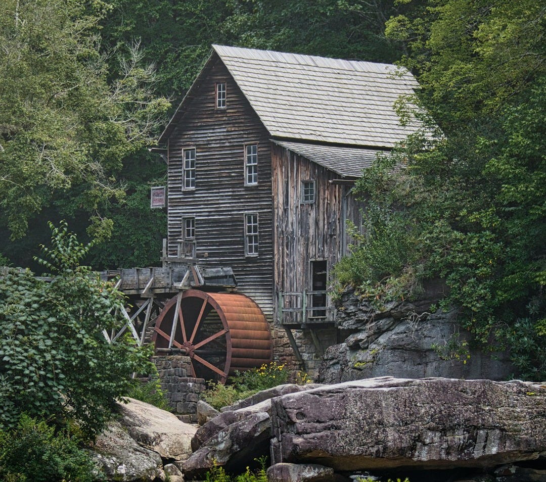 Wooden mill with water wheel beside waterfall